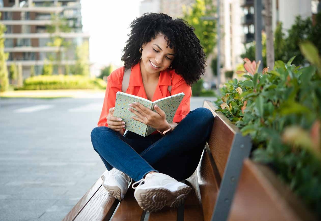 Woman reading a book outdoors on a bench