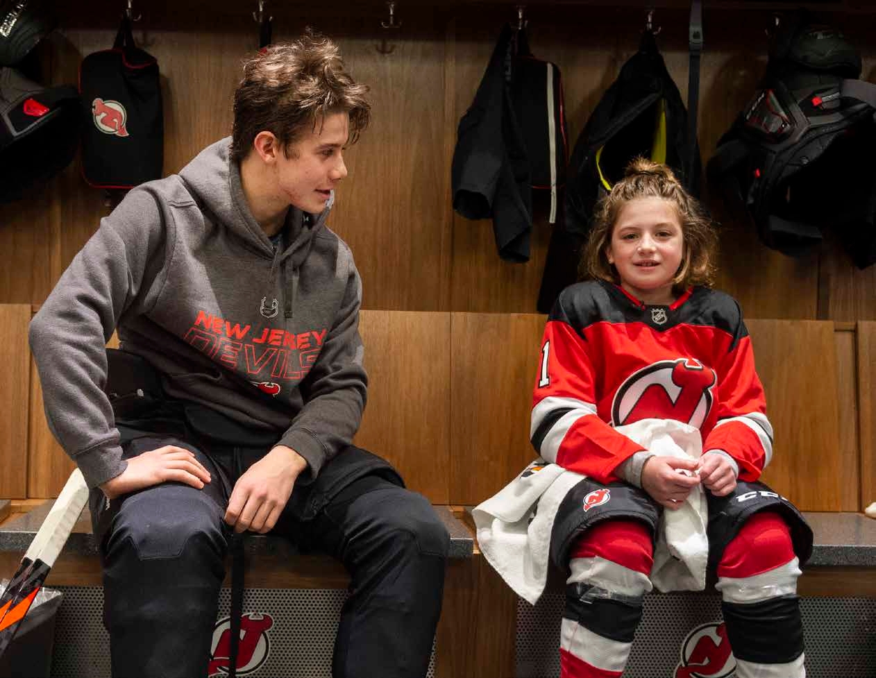 Jack Hughes and a young New Jersey Devils fan in the team locker room